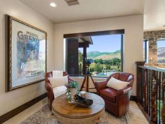 Experience breathtaking mountain views from this cozy reading nook, featuring two plush leather armchairs and a unique rope-wrapped coffee table.
