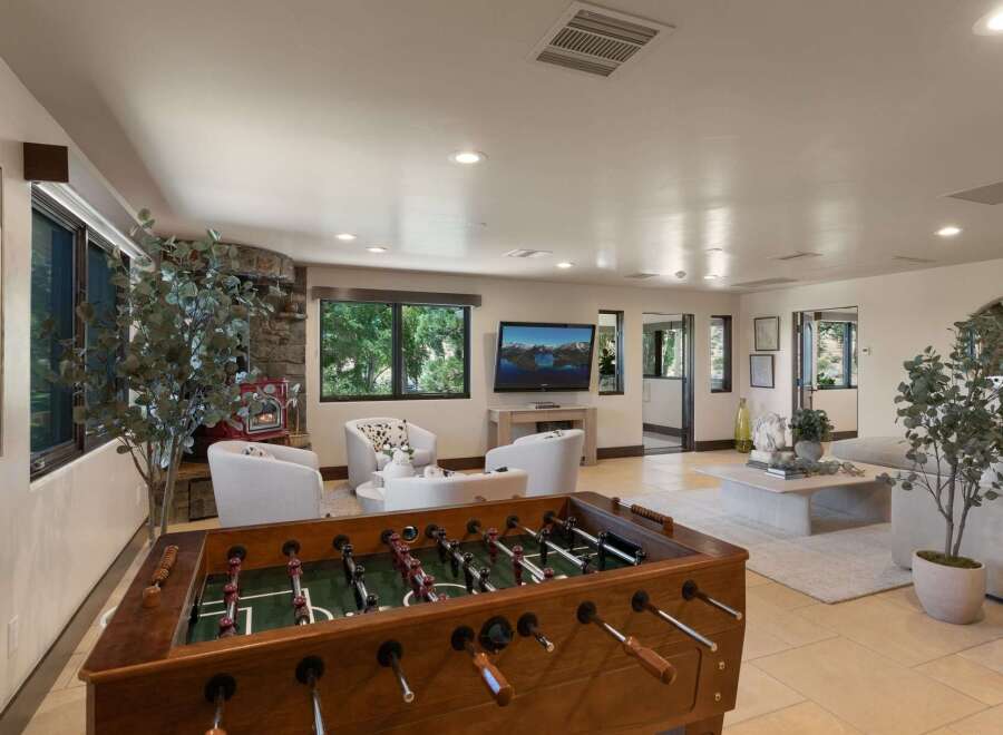 Experience ultimate relaxation and entertainment in this spacious living area, featuring a cozy fireplace and a large foosball table perfect for friendly competition.