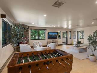 Experience ultimate relaxation and entertainment in this spacious living area, featuring a cozy fireplace and a large foosball table perfect for friendly competition.