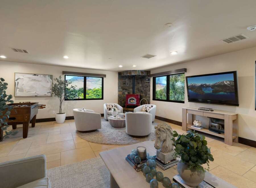 Experience breathtaking mountain views from this inviting living space, featuring a cozy stone fireplace and a vibrant red wood-burning stove.