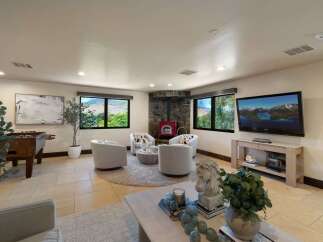 Experience breathtaking mountain views from this inviting living space, featuring a cozy stone fireplace and a vibrant red wood-burning stove.
