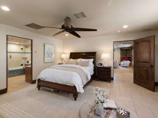Experience luxurious comfort in this master suite, featuring a spacious king-sized bed adorned with crisp white linens and plush pillows.