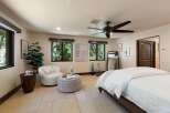This inviting bedroom offers a serene retreat with ample natural light streaming through large windows, showcasing lush outdoor views.