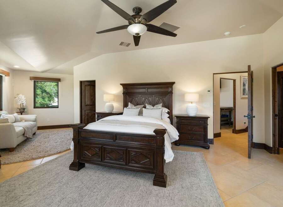Experience luxury in this spacious master suite, featuring a grand dark wood bed as the centerpiece and elegant white lamps on matching nightstands.