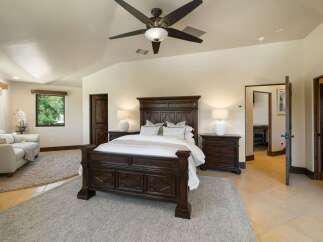 Experience luxury in this spacious master suite, featuring a grand dark wood bed as the centerpiece and elegant white lamps on matching nightstands.