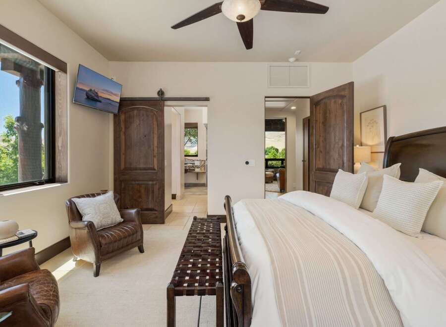 Experience luxury and comfort in this master bedroom, featuring a plush king-sized bed with elegant linens and a cozy leather armchair.