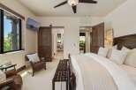 Experience luxury and comfort in this master bedroom, featuring a plush king-sized bed with elegant linens and a cozy leather armchair.