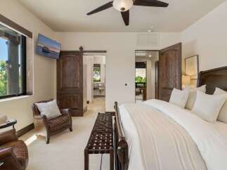 Experience luxury and comfort in this master bedroom, featuring a plush king-sized bed with elegant linens and a cozy leather armchair.