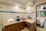This luxurious bathroom features a stunning blue vessel sink atop a custom wood vanity, complemented by a decorative tile backsplash.