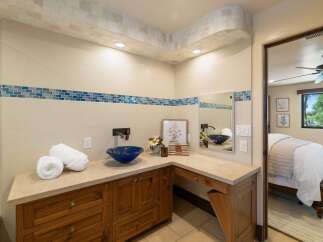 This luxurious bathroom features a stunning blue vessel sink atop a custom wood vanity, complemented by a decorative tile backsplash.