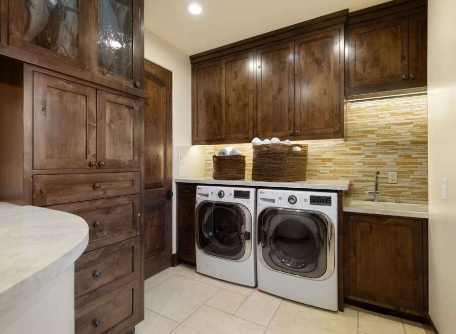 This laundry room boasts custom dark wood cabinetry, providing ample storage and a luxurious feel.