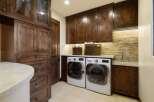 This laundry room boasts custom dark wood cabinetry, providing ample storage and a luxurious feel.