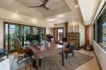 This spacious home office features a large wooden desk with a leather inlay, complemented by a comfortable executive chair and two accent chairs.