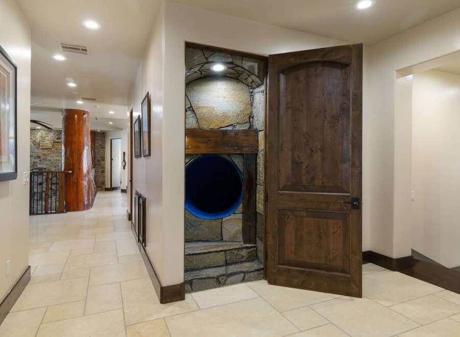 Discover a unique home with a playful twist, featuring a hidden tunnel entrance built into a stone-clad alcove.