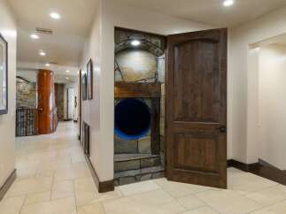 Discover a unique home with a playful twist, featuring a hidden tunnel entrance built into a stone-clad alcove.