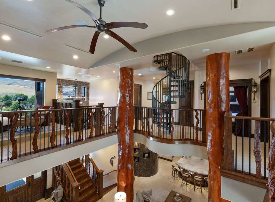Experience rustic luxury in this grand entryway featuring a stunning spiral staircase and a massive log pillar.