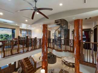 Experience rustic luxury in this grand entryway featuring a stunning spiral staircase and a massive log pillar.