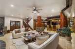 Step into a rustic-chic living space featuring a cozy seating area with plush sofas and a unique tree-trunk-inspired bar.
