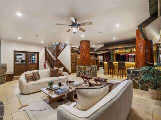 Step into a rustic-chic living space featuring a cozy seating area with plush sofas and a unique tree-trunk-inspired bar.