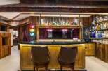 Step into a unique entertainment space featuring a rustic wooden bar with a granite countertop, illuminated by warm under-lighting.