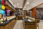 Step into this rustic home bar, featuring a stunning wooden bar top and custom cabinetry.