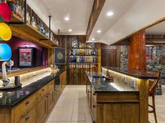 Step into this rustic home bar, featuring a stunning wooden bar top and custom cabinetry.