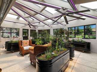 Experience year-round gardening in this stunning sunroom, featuring a retractable roof and integrated grow lights for optimal plant growth.