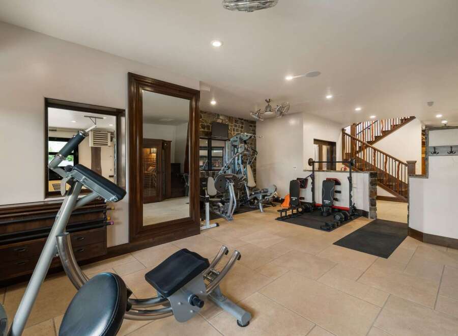 This home gym features a variety of weight training equipment, including a multi-station weight machine and adjustable benches.