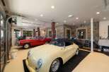 This stunning garage boasts a pristine collection of classic cars, including a vibrant red coupe and a charming cream convertible.