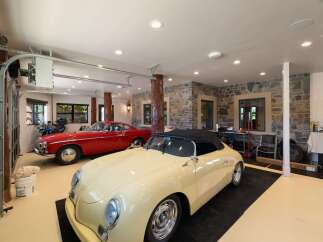This stunning garage boasts a pristine collection of classic cars, including a vibrant red coupe and a charming cream convertible.