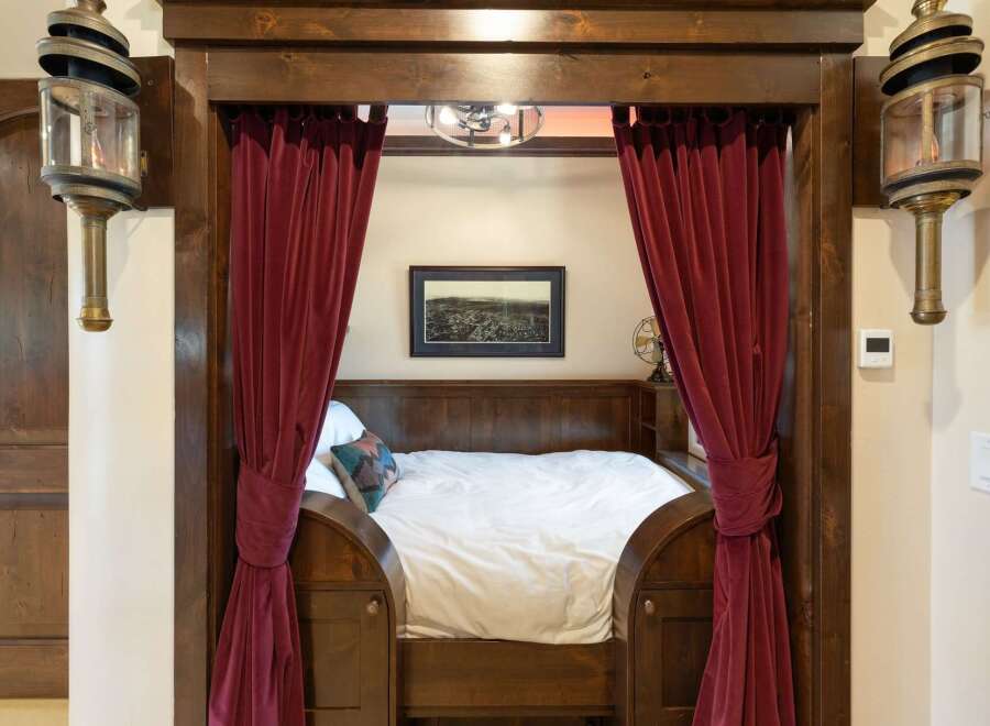 Step into a unique sleeping nook, featuring rich wooden accents and luxurious deep red velvet curtains that create a cozy, private retreat.