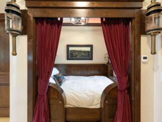 Step into a unique sleeping nook, featuring rich wooden accents and luxurious deep red velvet curtains that create a cozy, private retreat.