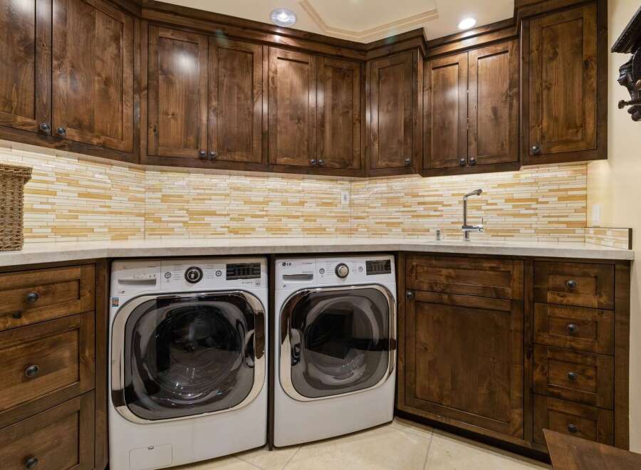 This laundry room boasts custom dark wood cabinetry, providing ample storage and a luxurious feel.