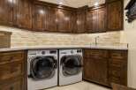 This laundry room boasts custom dark wood cabinetry, providing ample storage and a luxurious feel.