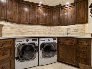 This laundry room boasts custom dark wood cabinetry, providing ample storage and a luxurious feel.
