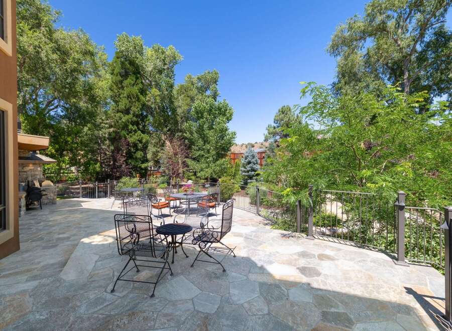 Enjoy outdoor living on this expansive stone patio, perfect for entertaining or relaxing amidst lush greenery.