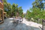 Enjoy outdoor living on this expansive stone patio, perfect for entertaining or relaxing amidst lush greenery.