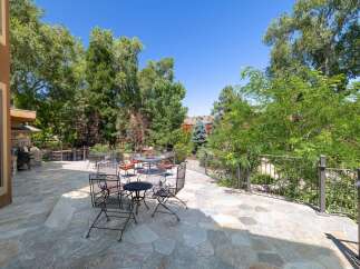 Enjoy outdoor living on this expansive stone patio, perfect for entertaining or relaxing amidst lush greenery.