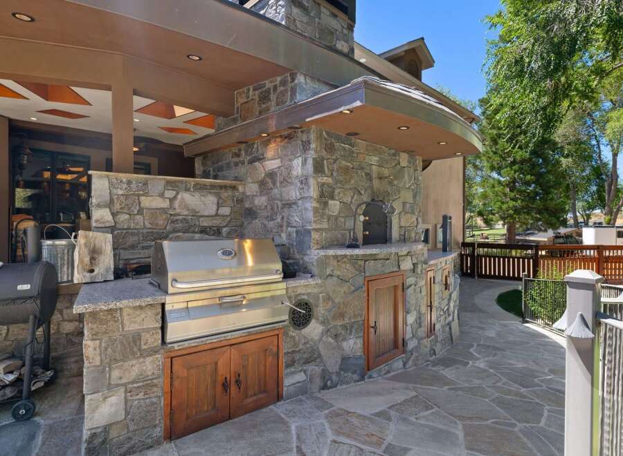 Experience the ultimate outdoor living with this luxurious stone outdoor kitchen, featuring a built-in grill, pizza oven, and ample storage.