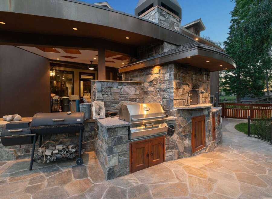 Experience luxury outdoor living with this stunning custom-built outdoor kitchen, featuring a built-in grill, pizza oven, and ample stone counter space.