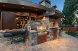 Experience luxury outdoor living with this stunning custom-built outdoor kitchen, featuring a built-in grill, pizza oven, and ample stone counter space.