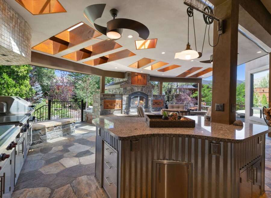 Experience luxurious outdoor living with this stunning covered patio, featuring a gourmet grill station and a cozy stone fireplace.