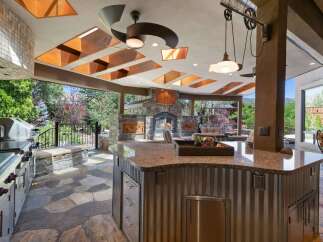 Experience luxurious outdoor living with this stunning covered patio, featuring a gourmet grill station and a cozy stone fireplace.