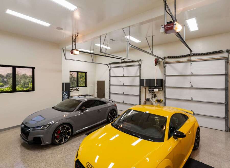 This spacious garage features two sleek Audi TT RS sports cars, one in a sophisticated grey and the other in a vibrant yellow.