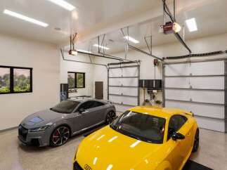 This spacious garage features two sleek Audi TT RS sports cars, one in a sophisticated grey and the other in a vibrant yellow.