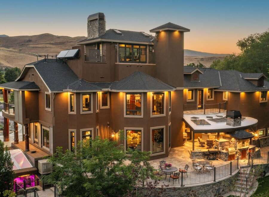 Experience luxury living in this stunning multi-story home, featuring a spacious outdoor entertainment area with a built-in grill and seating.