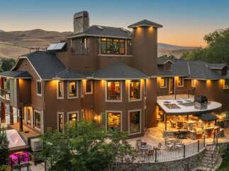 Experience luxury living in this stunning multi-story home, featuring a spacious outdoor entertainment area with a built-in grill and seating.