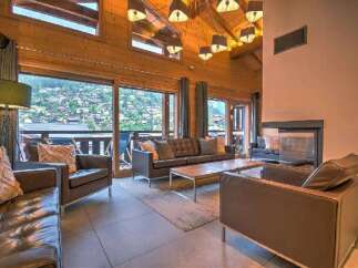Experience luxury mountain living in this stunning chalet featuring a spacious living area with a modern fireplace and expansive windows offering breathtaking views.