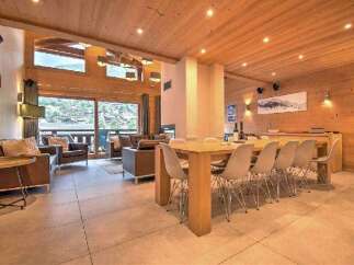 Experience luxurious mountain living in this stunning chalet, featuring a spacious open-plan living and dining area with a large wooden dining table perfect for gatherings.