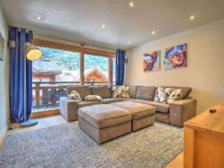 Experience mountain living in this inviting living room, featuring a spacious sectional sofa and plush ottomans perfect for relaxation.